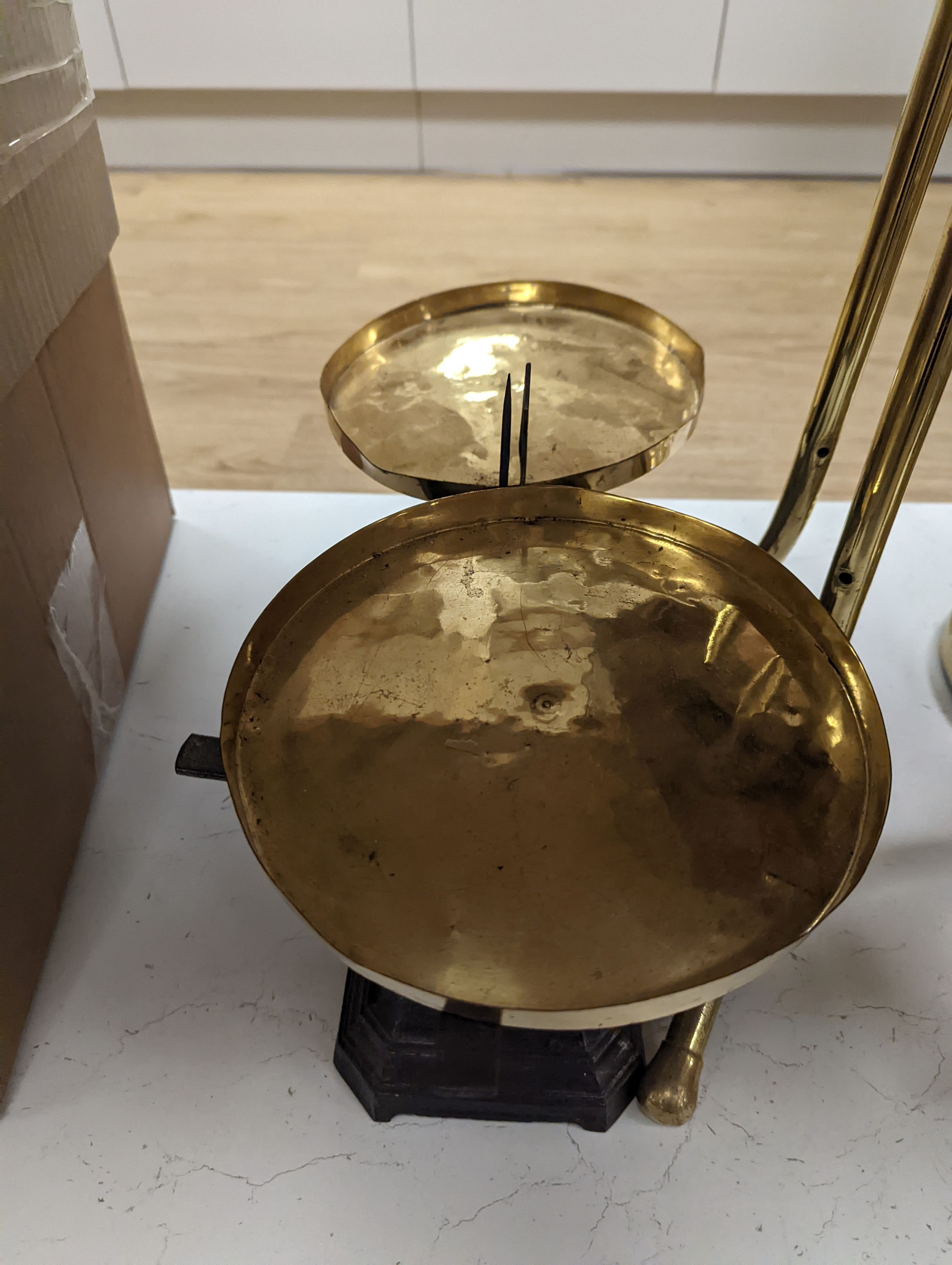 A brass magazine stand, a pair of scales, four candlesticks and a tall brass oil lamp base, Oil lamp 58 cms high.